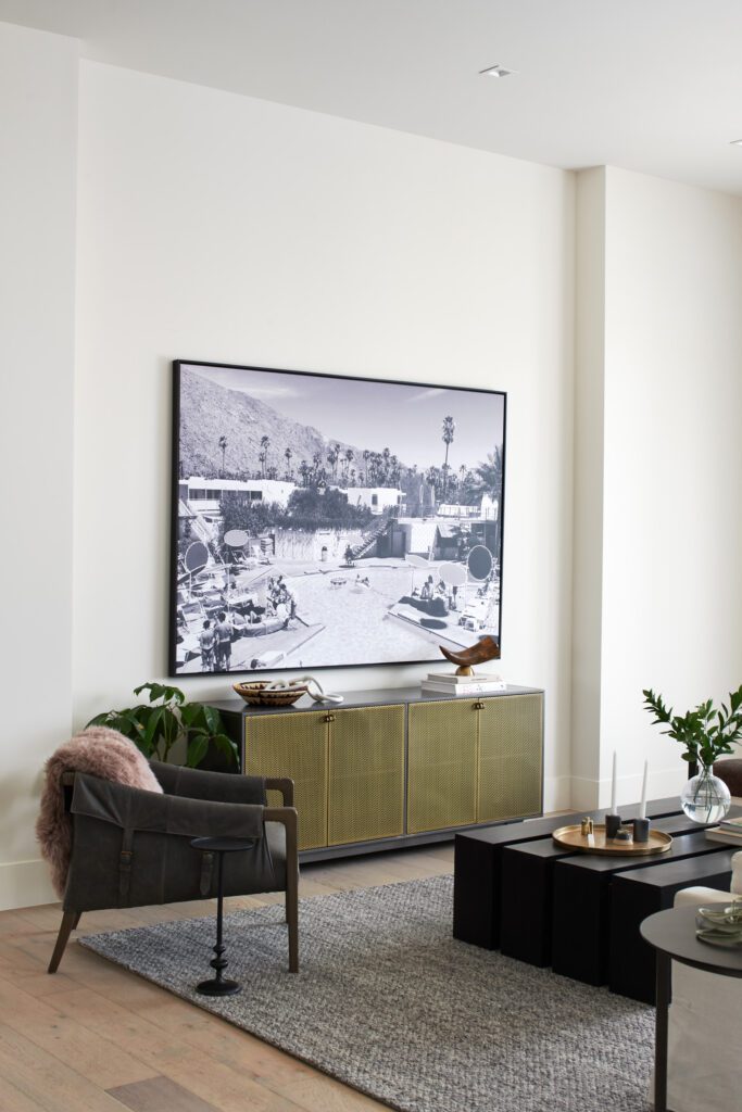 Living room corner with oversized black-and-white landscape photo, brass console, and layered decor.