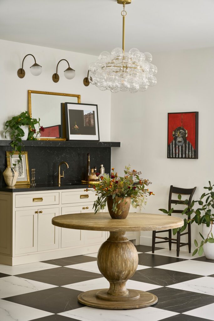 Bright breakfast nook with a round pedestal table, vintage lighting, curated art, and two-tone cabinetry.