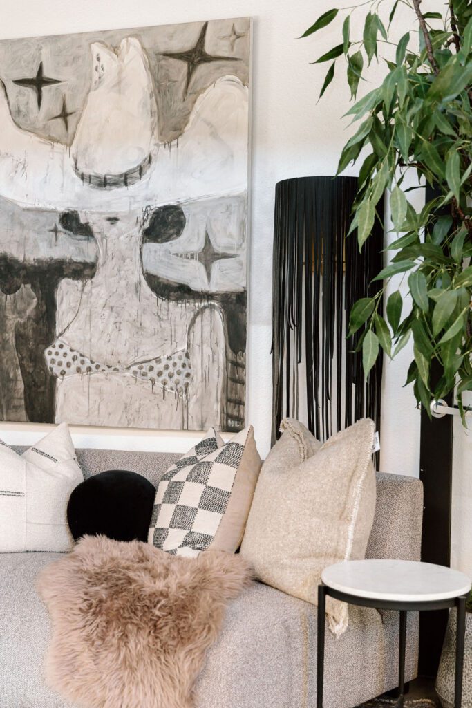 Eclectic lounge with colorful art, rattan chairs, sculptural stools, and desert-inspired palette.