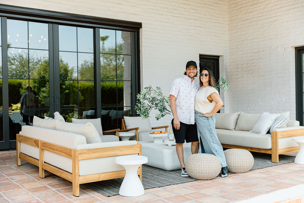 A happy couple enjoying a modern outdoor patio with comfortable lounge seating and a white coffee table, connected to a contemporary home in Phoenix.