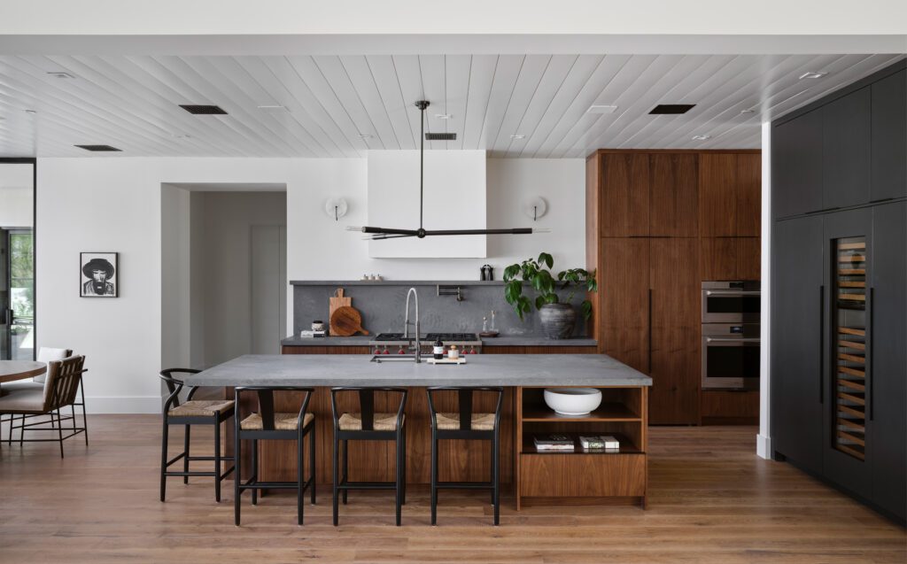 Modern luxury kitchen in a Scottsdale desert home with walnut cabinetry, black accents, and a concrete island designed for entertaining.