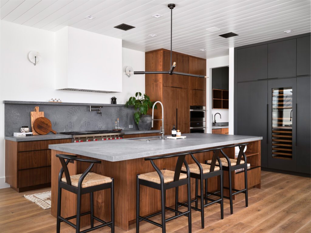 Contemporary kitchen with walnut cabinets, charcoal stone backsplash, and black modern lighting designed by Smyth House.