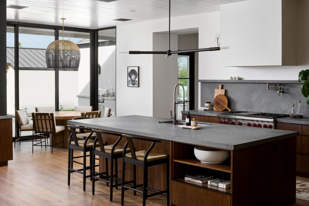 Luxury kitchen with integrated dining nook, large island, and black pendant lighting in a modern Scottsdale home.