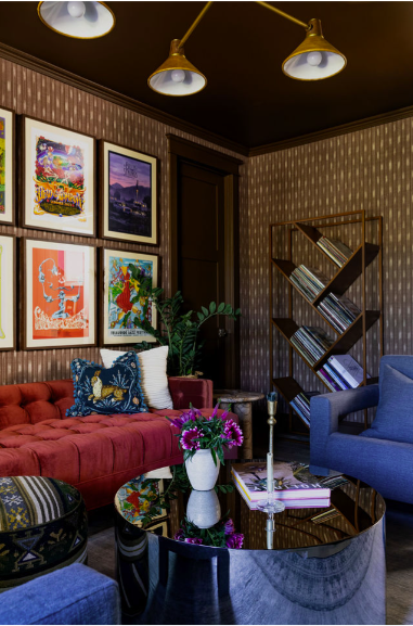 Cozy Zen Den featuring a deep tufted red sofa, eclectic gallery wall, sculptural brass lighting, geometric bookshelf, and layered textures that create a warm, creative retreat.