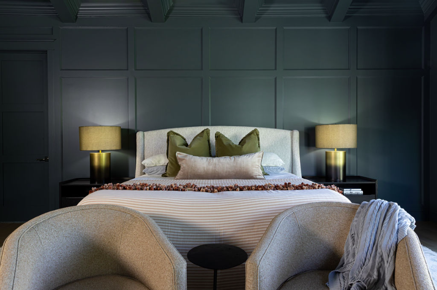 Moody bedroom showcasing 2026 interior design trends with deep blue paneled walls, layered tonal bedding, and sculptural lighting for a timeless, intentional feel.