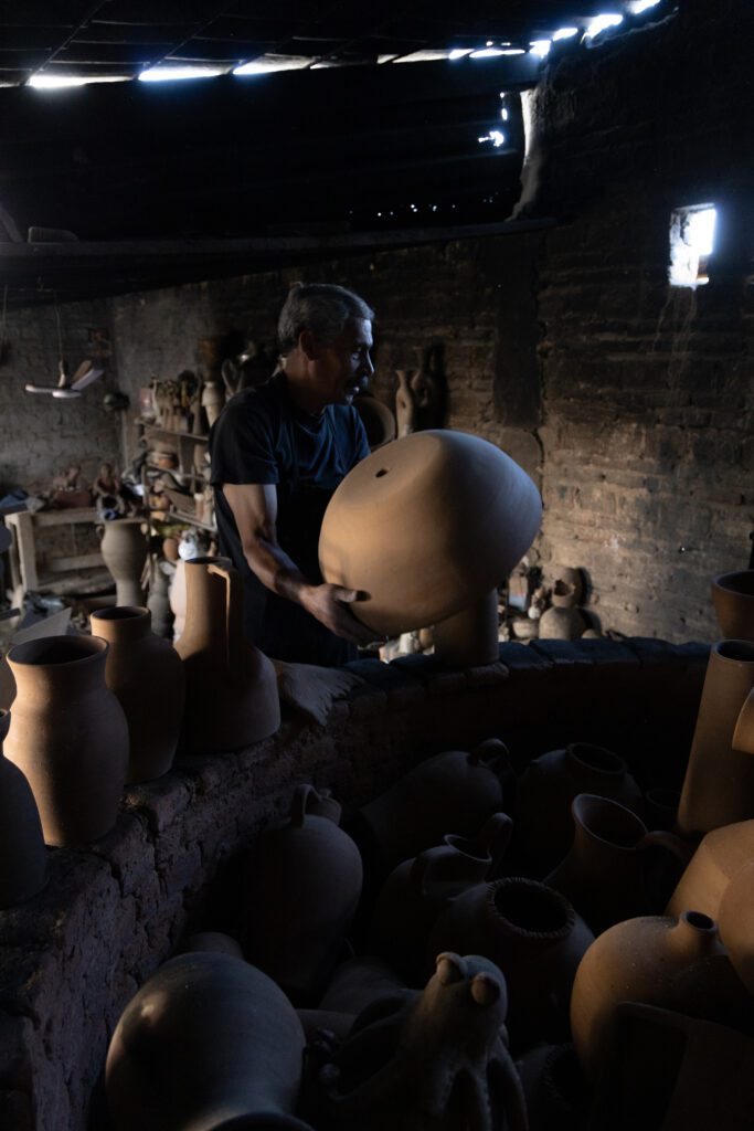 Artisan shaping a large handcrafted clay vessel in a traditional workshop in Mexico, highlighting the artisanal process behind the Smyth House x Palo Santo lighting collection.