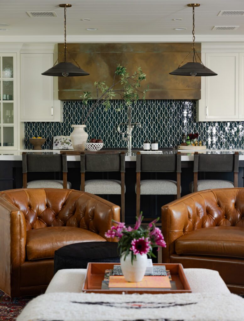 Open-concept living room and kitchen with leather chairs, patterned backsplash, and custom cabinetry in a Phoenix home.