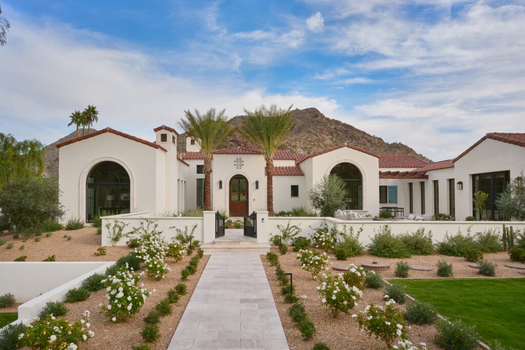 Mediterranean-inspired luxury home exterior with arched windows, desert landscaping, and mountain backdrop