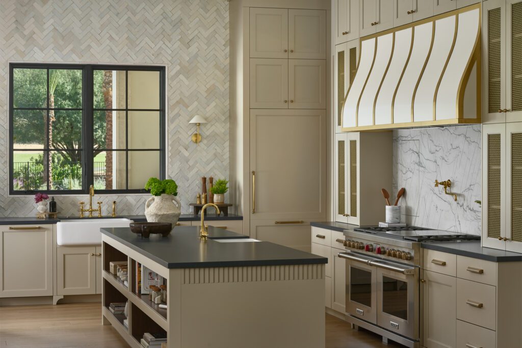 Custom luxury kitchen with brass range hood detail, marble backsplash, and designer cabinetry