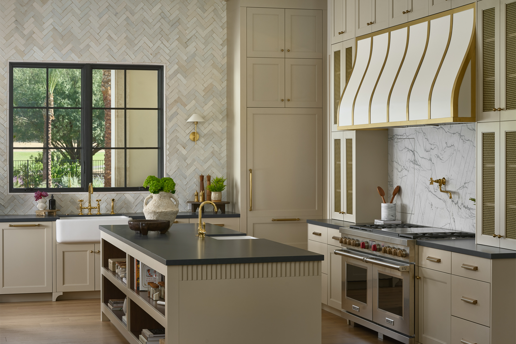 Custom luxury kitchen with brass range hood detail, marble backsplash, and designer cabinetry
