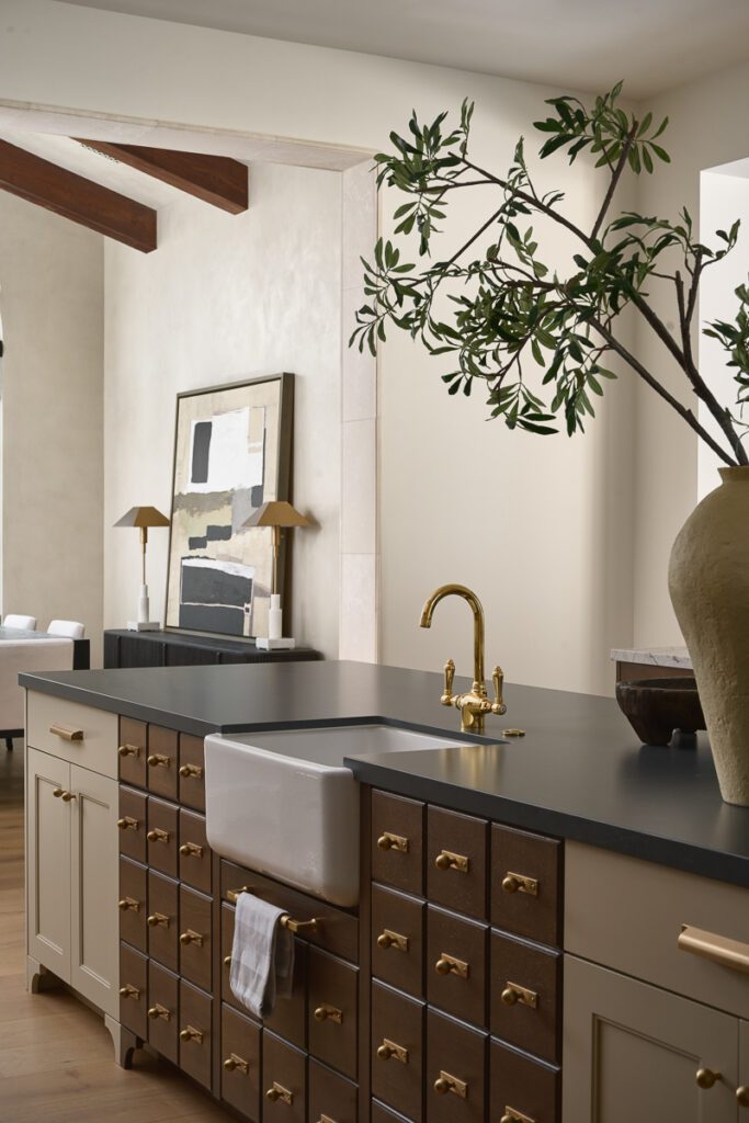 Luxury kitchen island with farmhouse sink, brass fixtures, and custom cabinetry