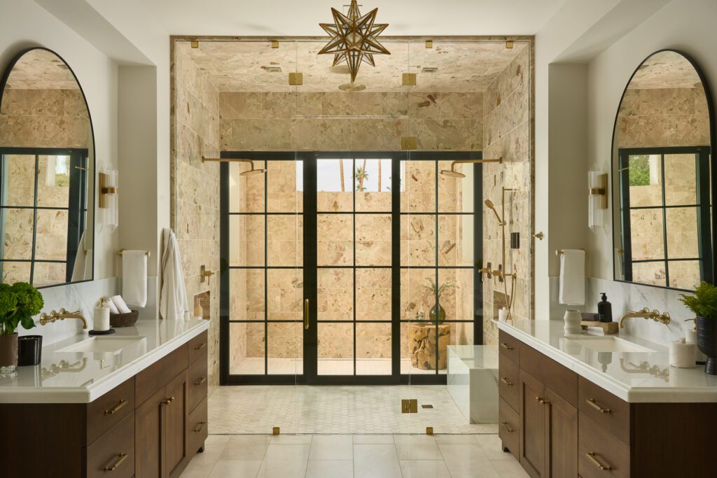Luxury primary bathroom with dual vanity, marble shower, and black framed glass doors