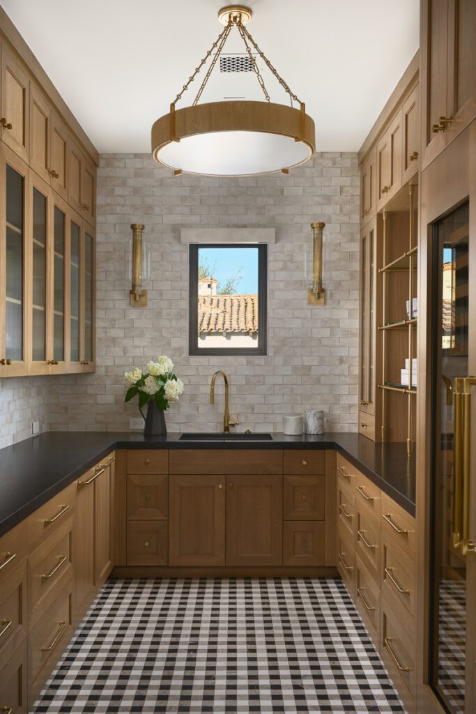 Luxury laundry room designed by Smyth House featuring custom wood cabinetry, layered lighting, natural stone surfaces, and functional entertaining spaces.