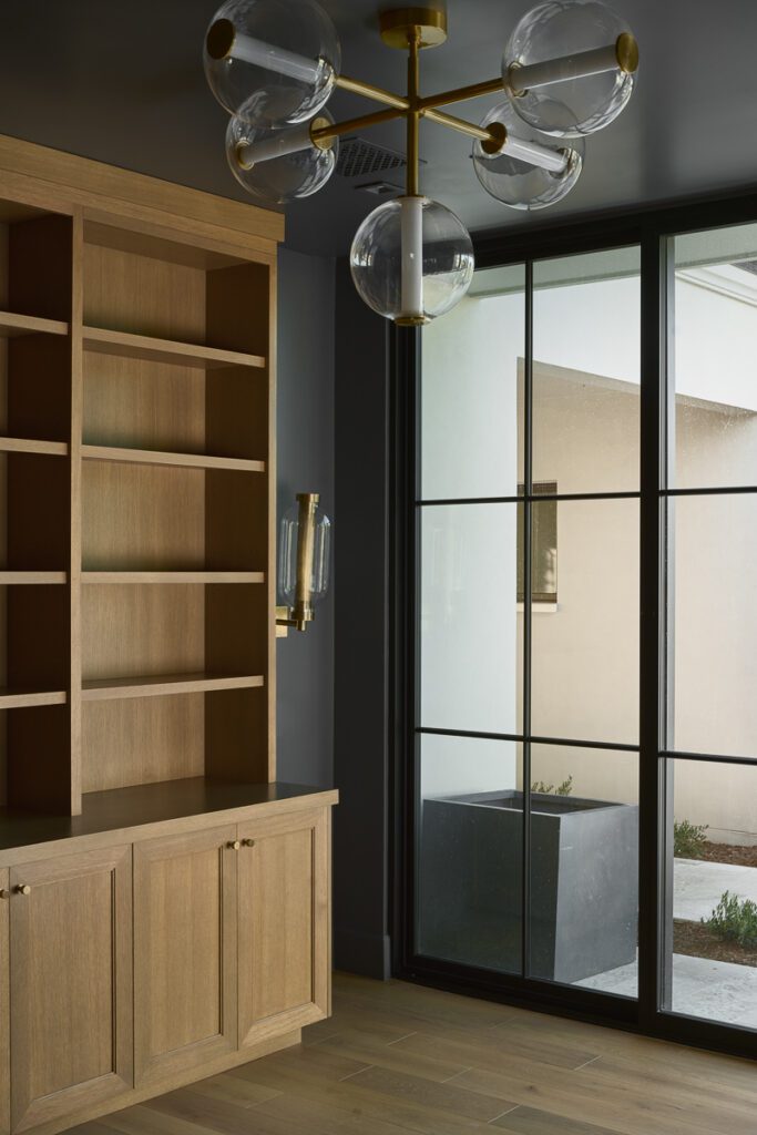Custom built-in cabinetry and steel-framed glass door designed by Smyth House featuring warm wood finishes, integrated storage, and modern luxury interior detailing.